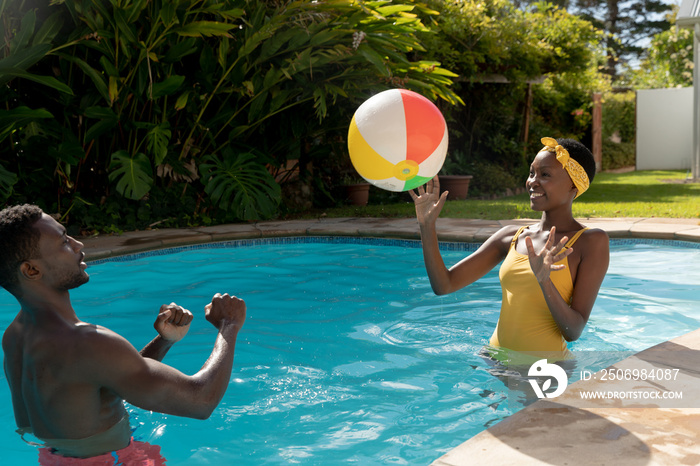 African american couple playing in swimming pool on sunny garden terrace