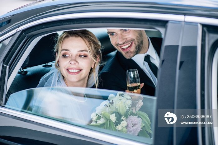 attractive bride and handsome bridegroom clinking with champagne glasses