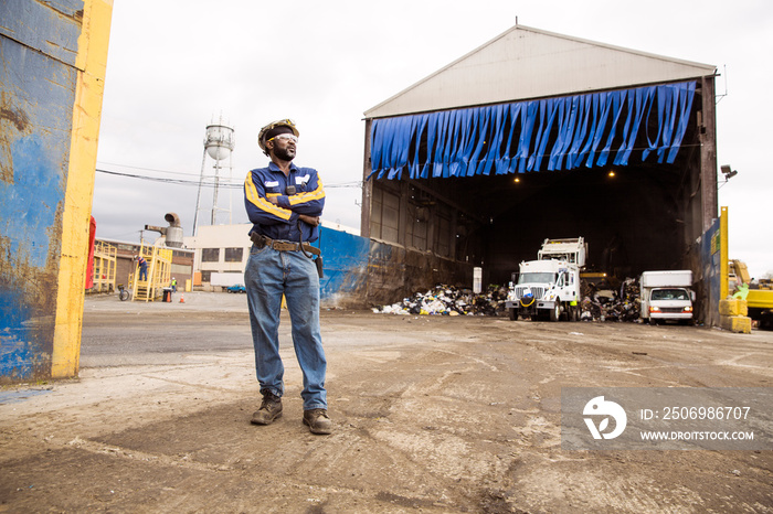 Worker standing next to hangar on recycling plant