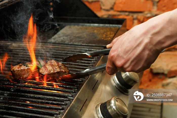 Man cooking meat steaks on professional grill outdoors