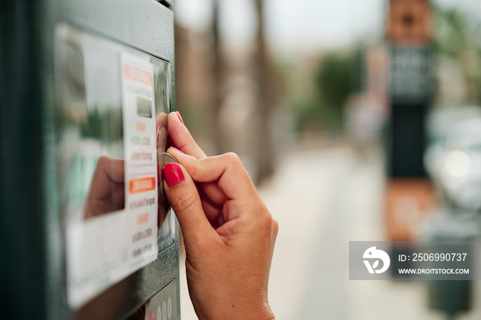 woman hands using coin in parking meter