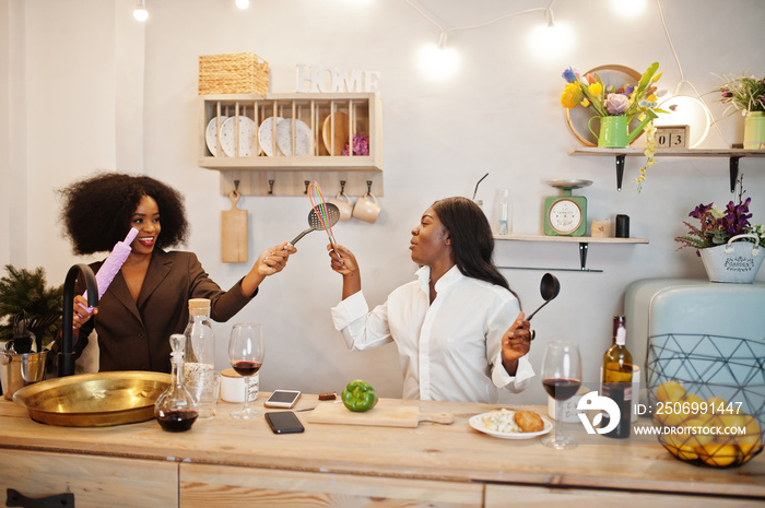 Two african american female friends women spending time at kitchen with wine. Black girlfriends  rel