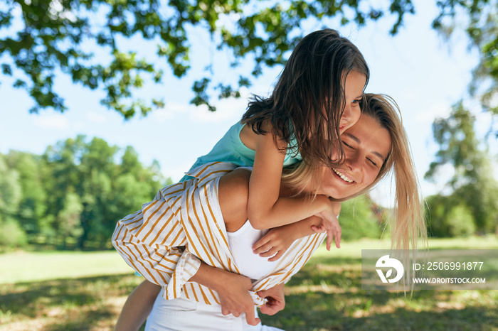 Happy mother and her daughter playing in the park during the picnic. Happy woman and little girl smi