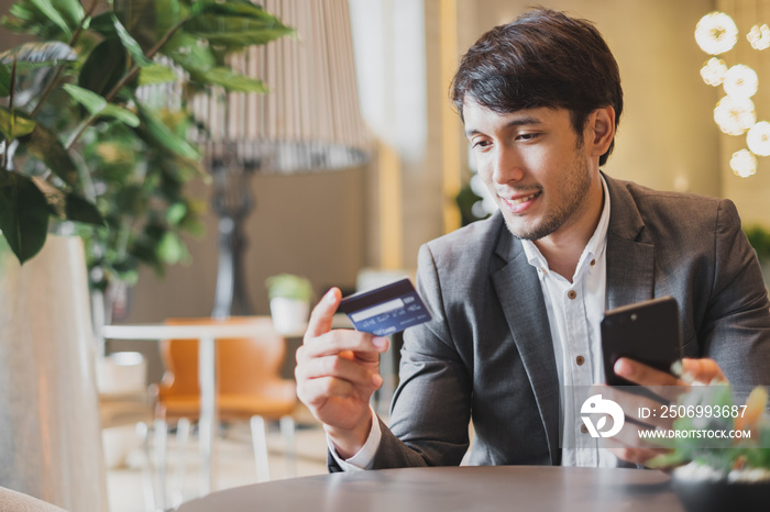 Asian businessman using credit card and mobile phone for online financial payment and shopping
