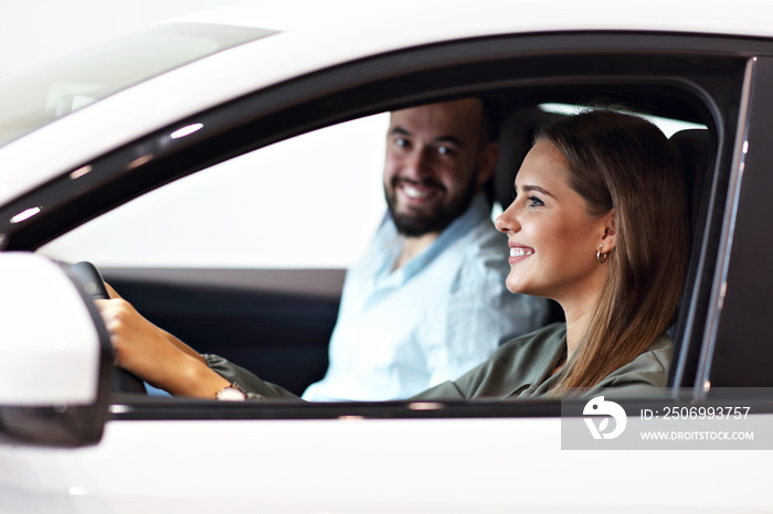 Adult couple choosing new car in showroom