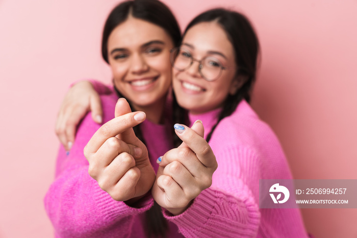 Image closeup of two teenage girls doing money gesture with hands