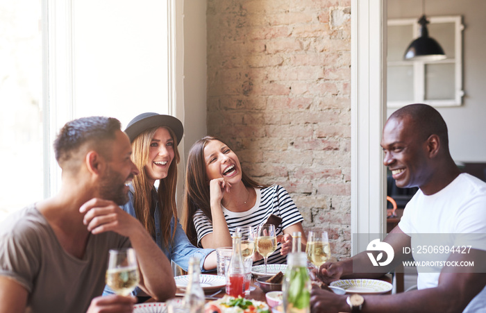 Four happy friends having wine and dinner together