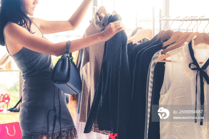 Beautiful woman shopping for clothes at retail apparel shop in the shopping mall. Modern trade lifes