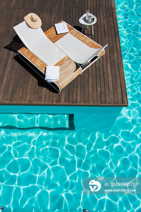 Lounge chairs at idyllic sunny summer poolside