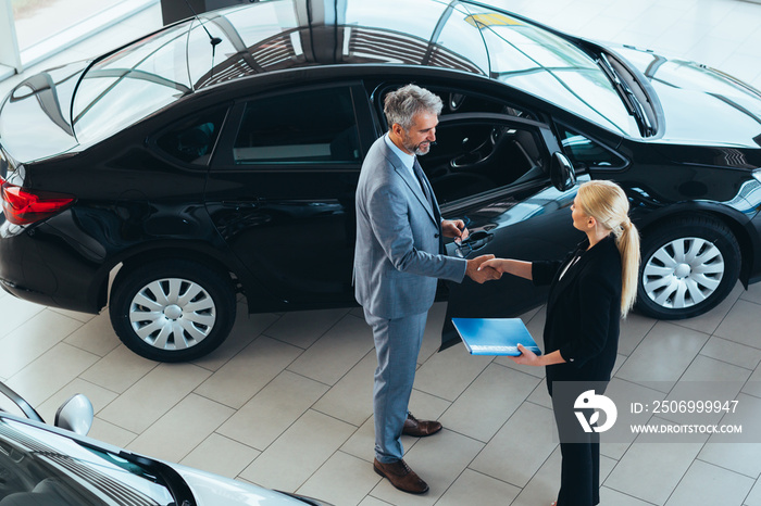 car sell agent handshake with client in car showroom