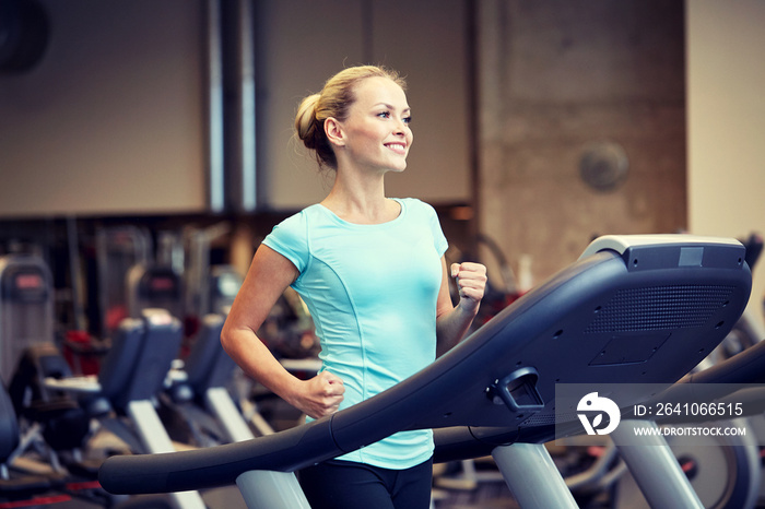 微笑的女人在健身房的跑步机上锻炼