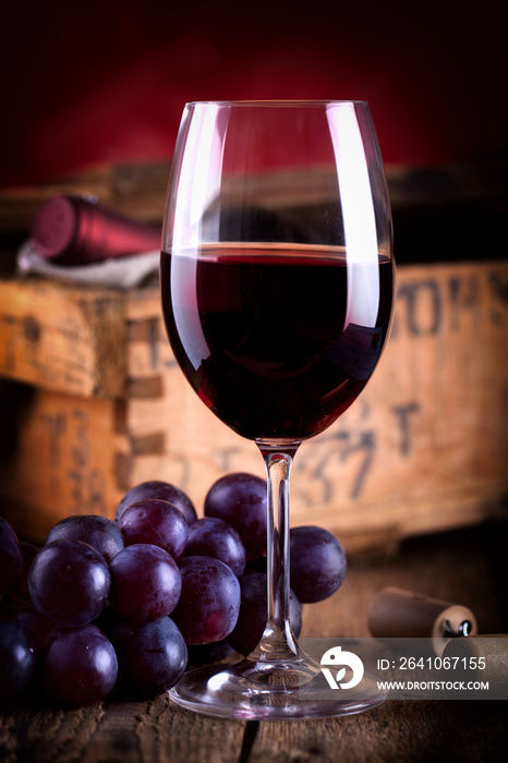 Glas Rotwein vor antiker Weinkiste