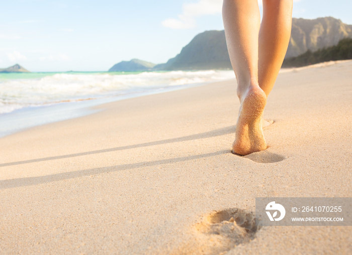 女人走在沙滩上，在沙滩上留下脚印。