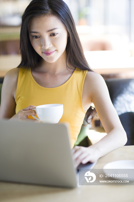 年轻女子在咖啡馆使用笔记本电脑