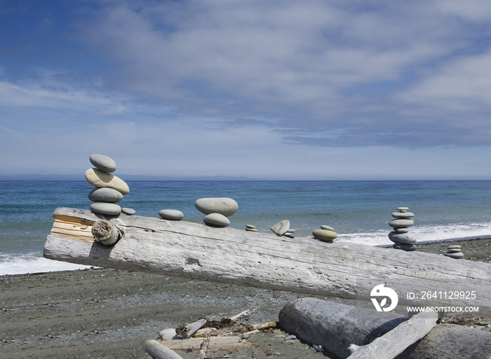 A pile of wood, with small stacks of rocks balanced on a wooden log