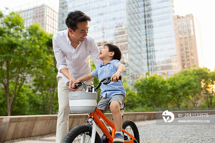 快乐的年轻爸爸教儿子骑自行车