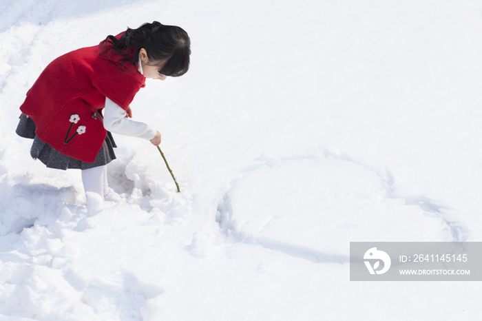 小女孩在雪地上画心型图案