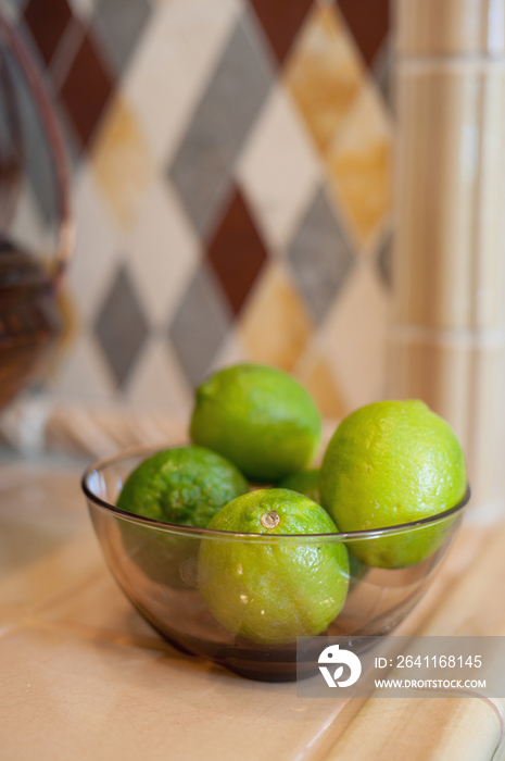 Close-up of oranges and pistachios in bowls against blurred backsplash on kitchen counter