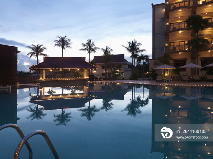 Illuminated hotel building with swimming pool at dusk