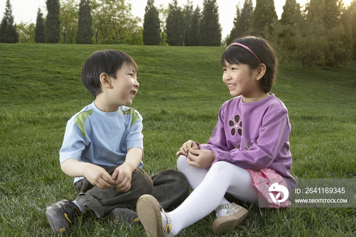 小男孩和小女孩坐在草地上