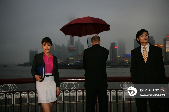 阴雨天外滩黄浦江边三位中外商务人士站立