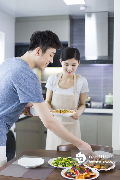 年轻夫妇摆餐桌准备吃饭