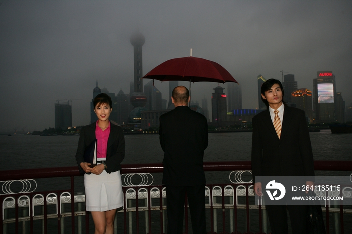 阴雨天外滩黄浦江边三位中外商务人士站立