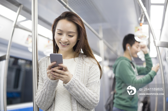 年轻女子在地铁里使用手机