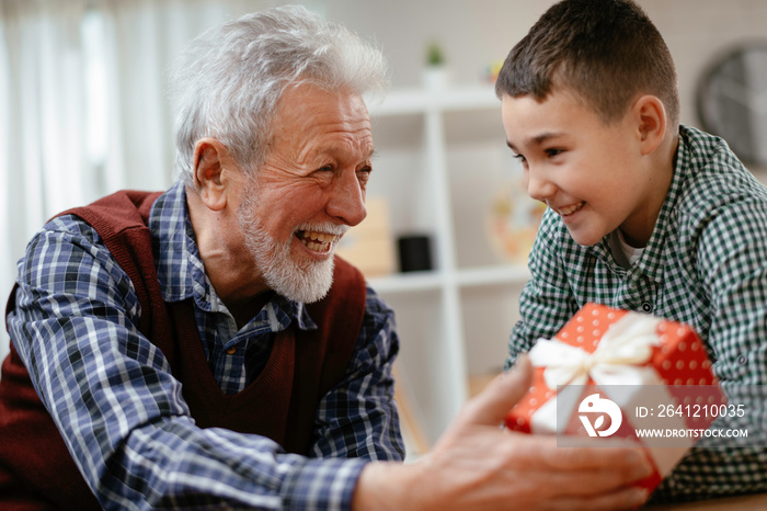 Grandfather giving gift to grandson. 