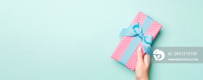 女人的手用彩纸包裹圣诞或其他节日手工制作的礼物。礼物盒，