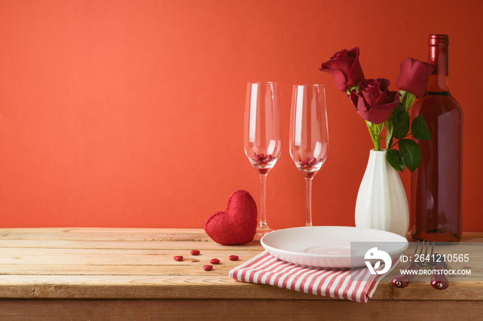 情人节浪漫晚餐概念。木制桌子，上面有盘子、酒瓶和玫瑰花