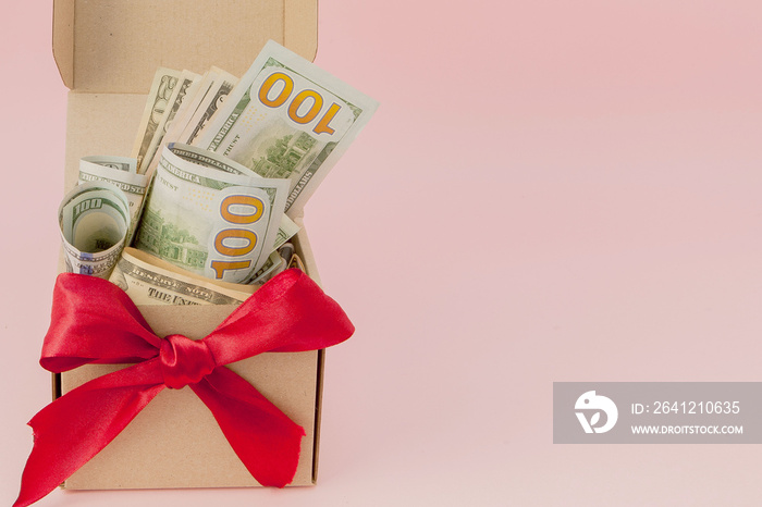 Gift box with dollars on pink background close up