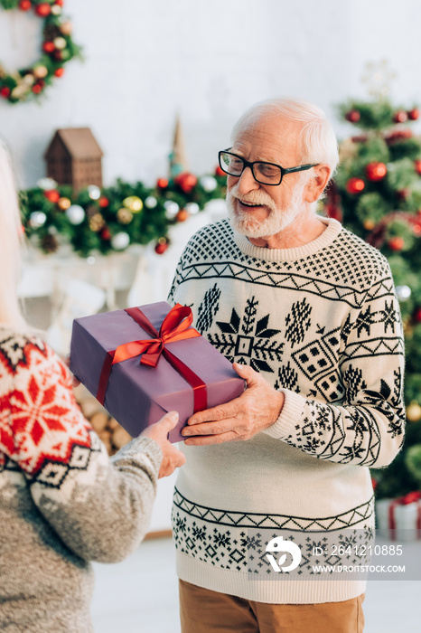 selective focus of joyful senior man taking gift box from wife