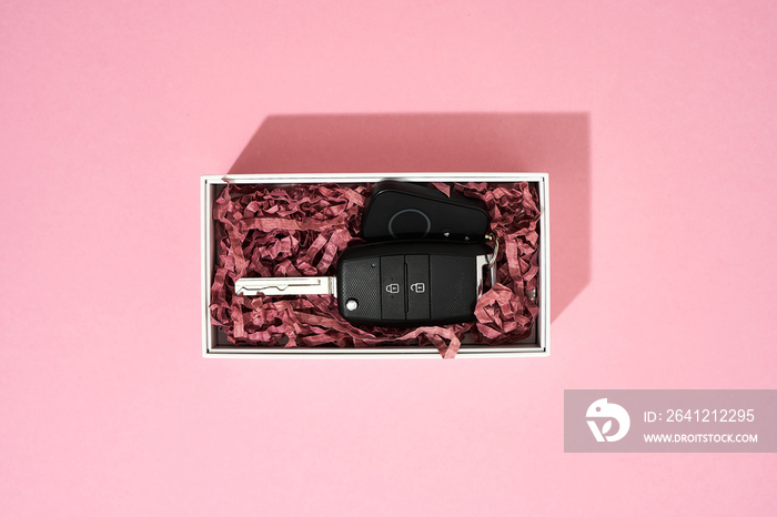 Presents for International Womens Day. Top view of a car key in gift box on pastel pink background