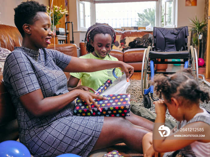 Family with girls wrapping birthday present