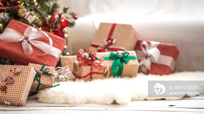 Pile of Christmas presents over light background on wooden table with cozy rug. Christmas decoration