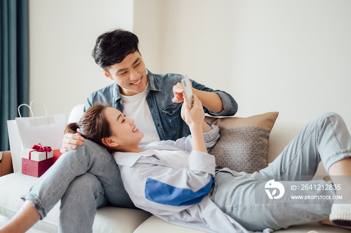 Young Asian couple at home using a smartphone