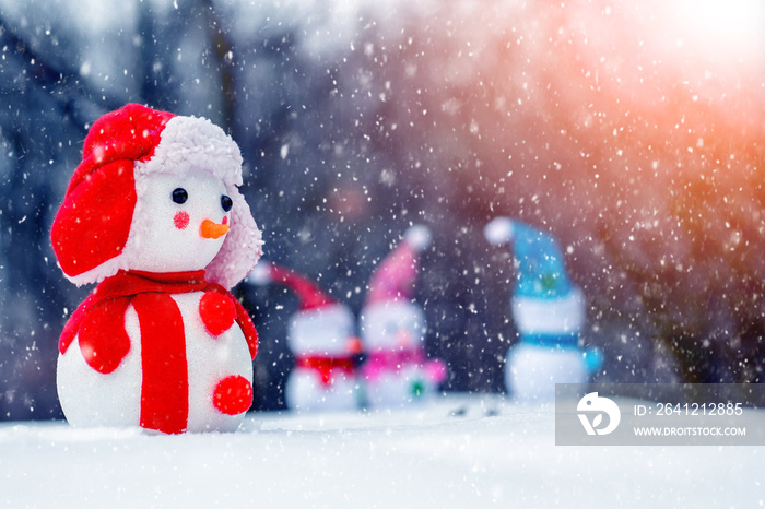 Christmas and New Year card with snowmen in the winter forest during a blizzard in the light of the 