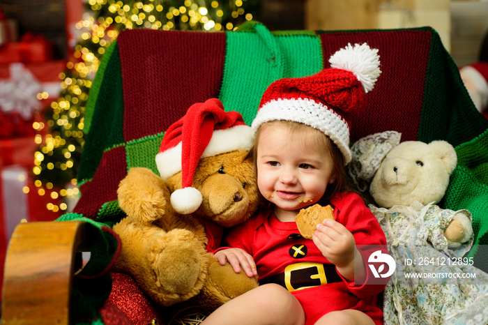 Cute baby face in Santa hat near Christmas tree. New year kids. Babyhood, childhood and people conce