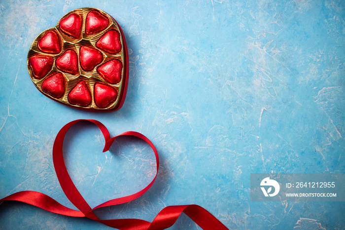 Valentines Day background with red heart and chocolate bonbons. Heart shape from ribbons. Top view, 