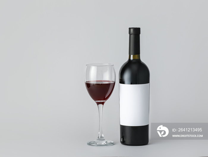 Bottle of wine with blank label and glass on light background