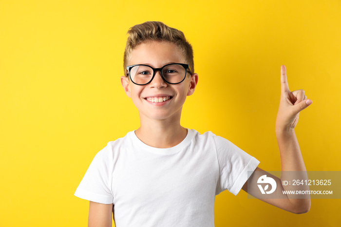 Happy boy in glasses against yellow background, space for text