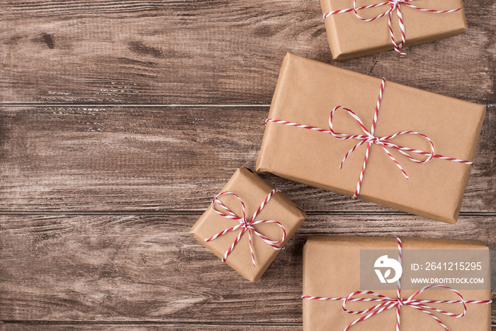 Top close up flatlay photo of pile of boxes packed in craft paper with red and white striped rope ly