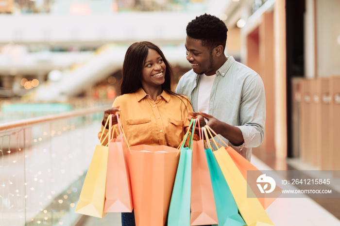 Happy black couple holding shopping bags looking at each other