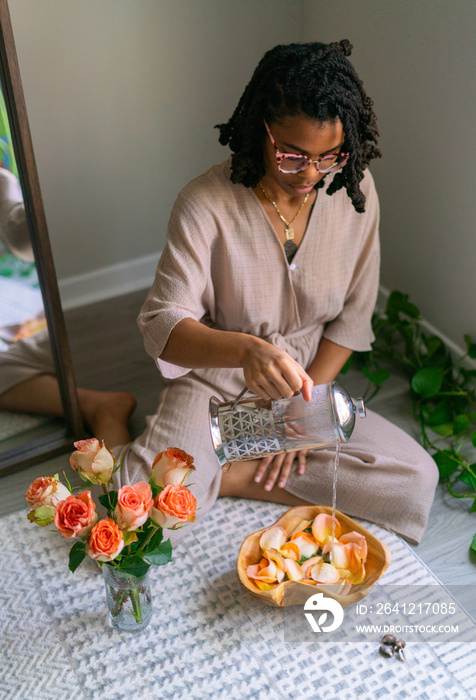 Young woman pouring water into bowl of flowers