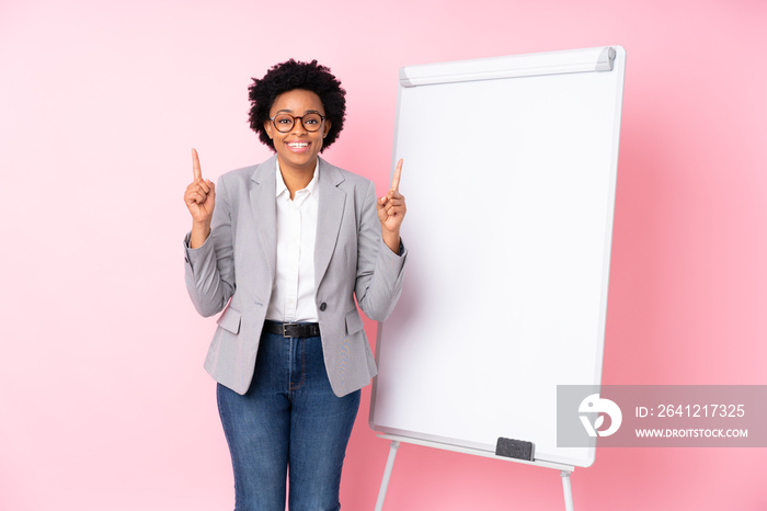 African american business woman giving a presentation on white board over isolated pink background p