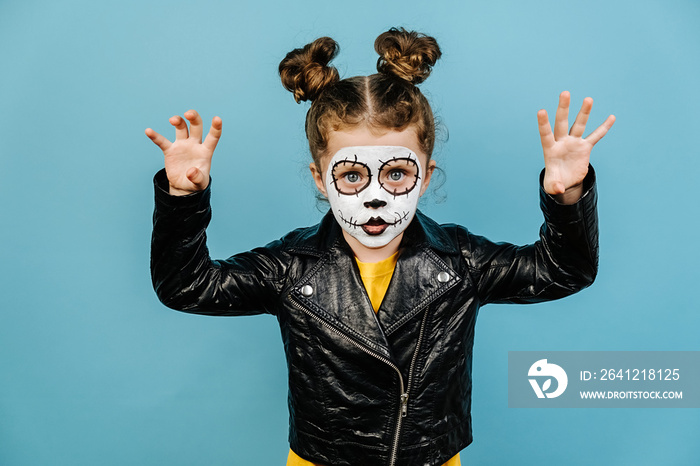 Shocked little preschool girl wears frightening makeup, keeps palms raised, scares someone, celebrat