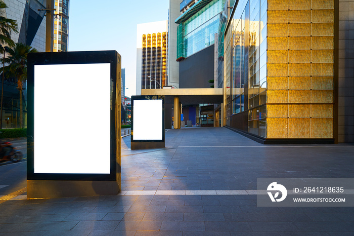 Two blank advertising stand at early morning against office building.