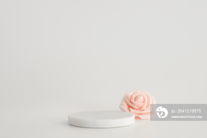 White marble podium on the white background with pink flowers. Podium for product, cosmetic presenta