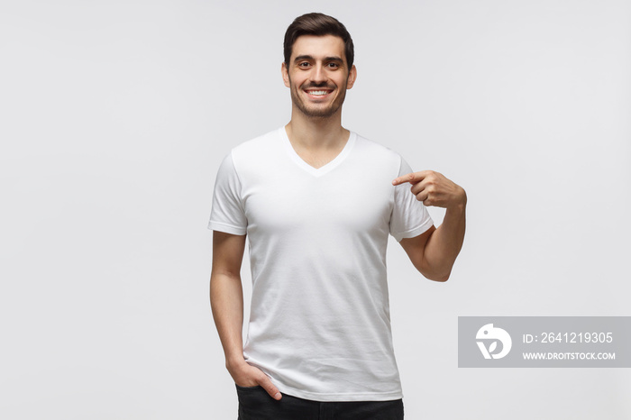 Young man pointing with index finger at blank  t-shirt with empty space for your advertising text or